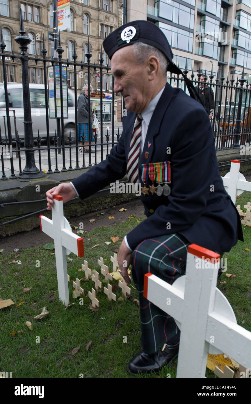 Veteran kneeling near cross at Remembrance day ceremony in Edinburgh, November 2005 Stock Photo
