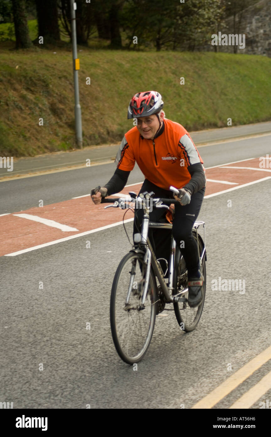 Middle aged man cycling to work up on the road Penglais Hill