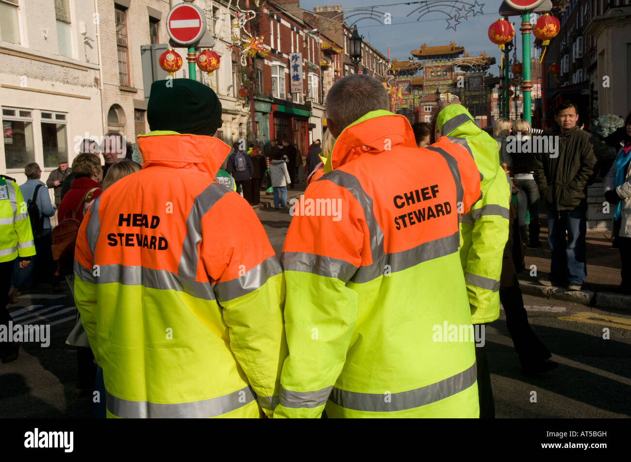 Two stewards wearing yellow and orange high visibility reflective jackets Chinese new year celebrations Liverpool England UK Stock Photo