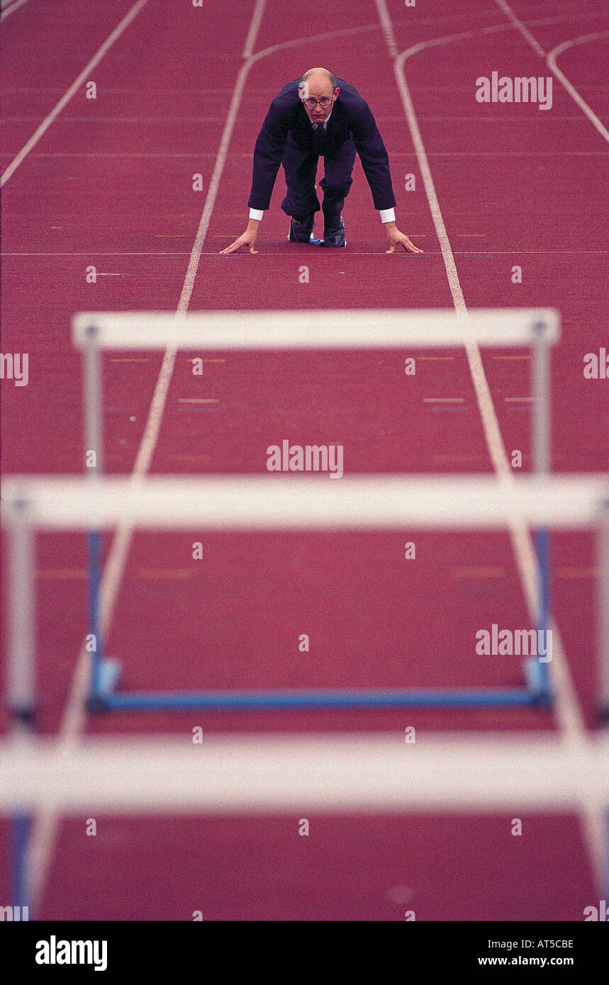 suited man on starting blocks of hurdle running track Stock Photo Alamy