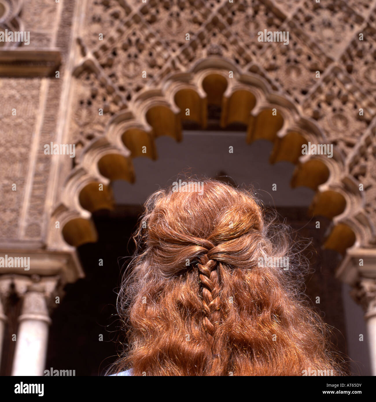 A woman with plaited red hair looking at architectural detail at the Real Alcazar in Seville Spain  KATHY DEWITT Stock Photo