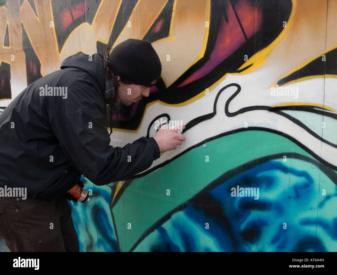 Graffiti artists spray painting building site hoarding Liverpool Stock