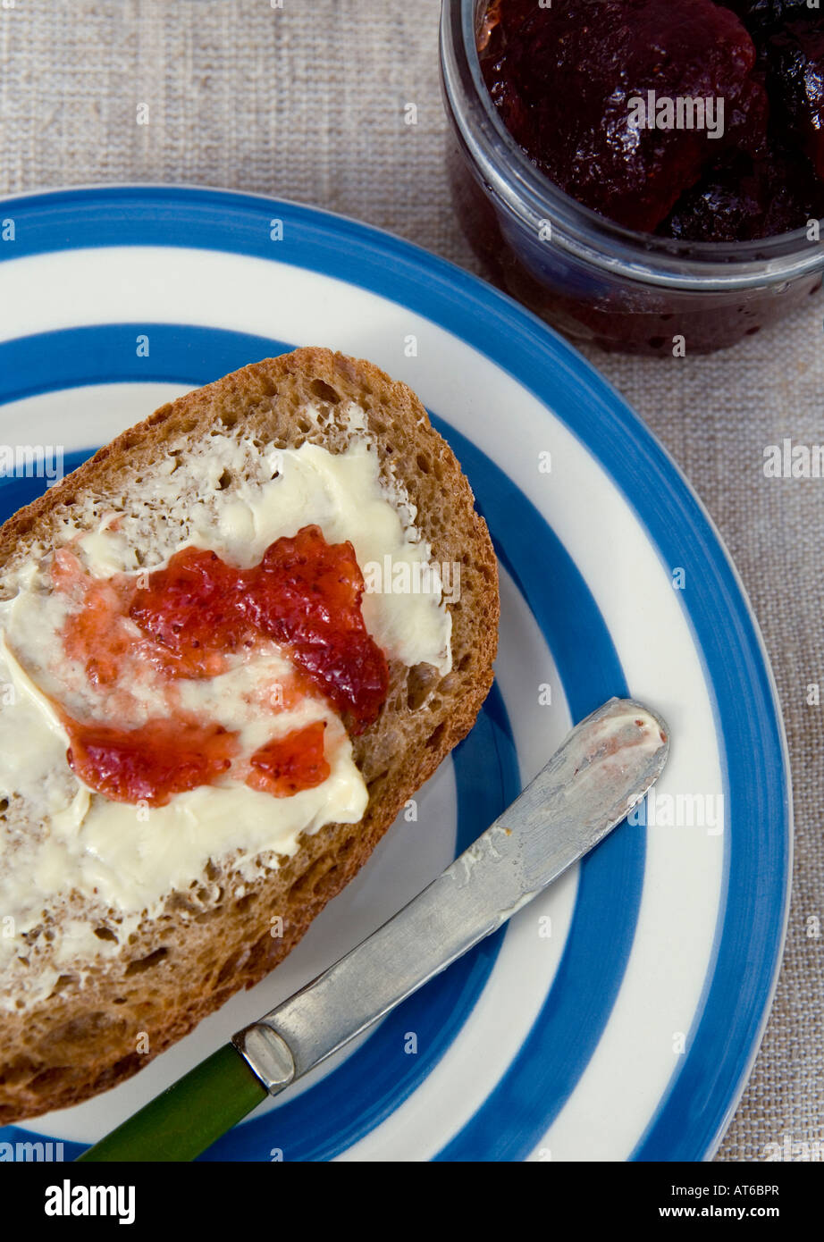 Wholemeal bread spread with organic butter and strawberry jam Stock Photo