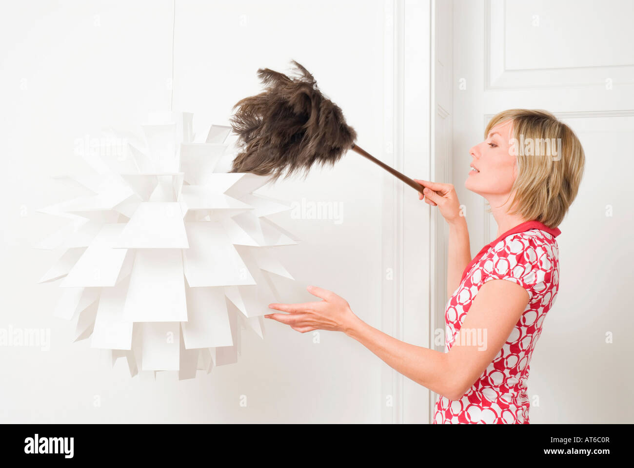 Woman dusting a lamp with a feather duster Stock Photo Alamy