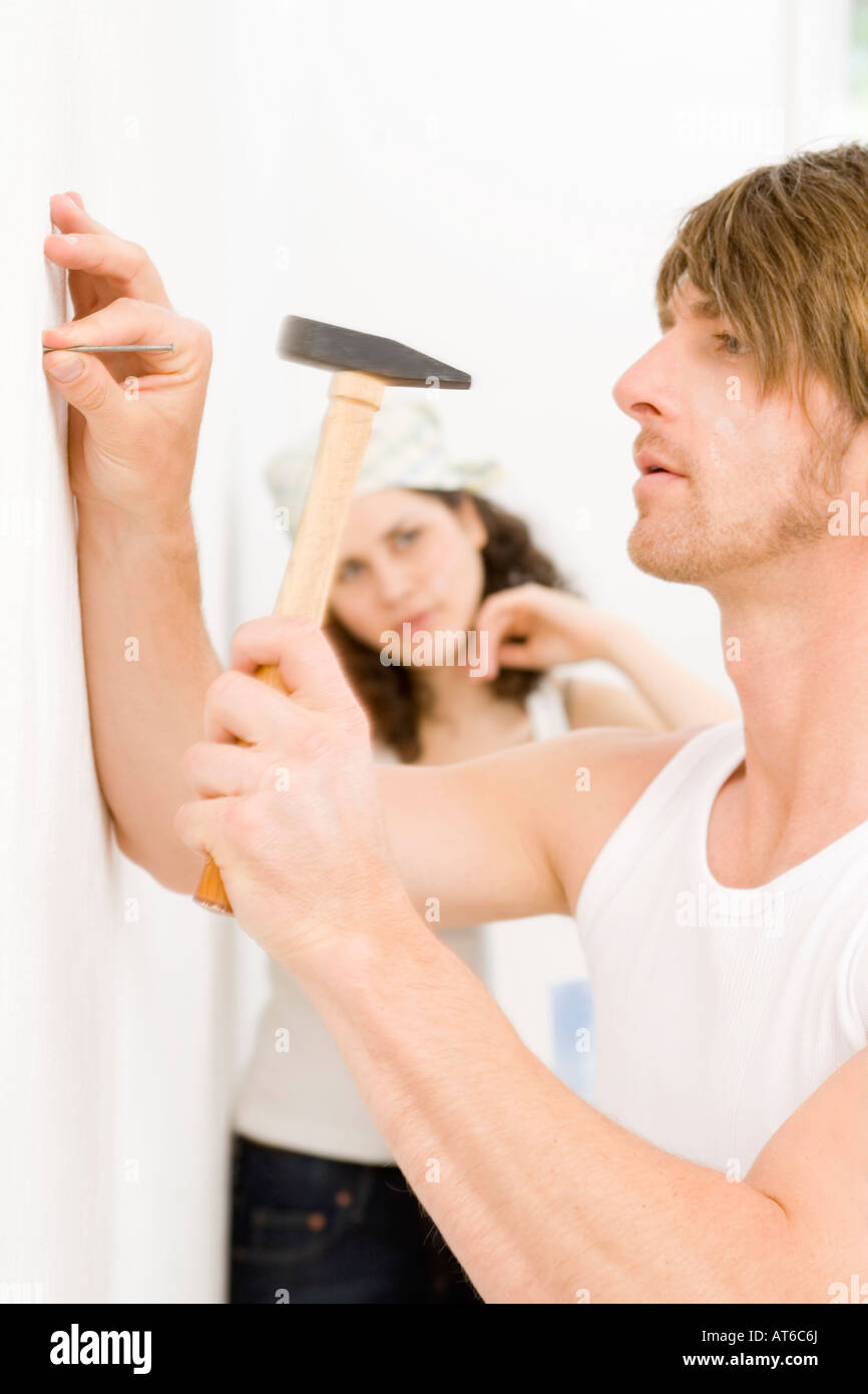 Young man hammering nail into wall Stock Photo Alamy
