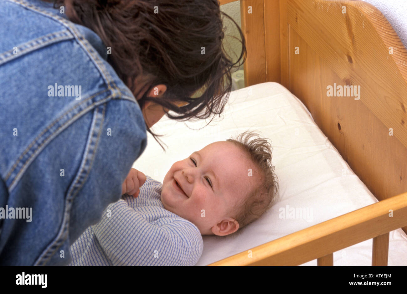 Mother puts baby in bed Stock Photo