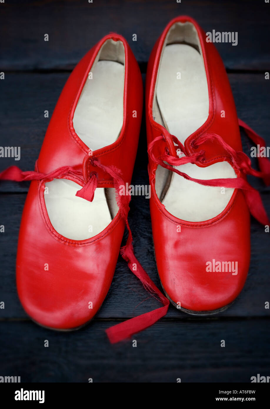 A pair of vintage red tap shoes shot against polished dark wooden floor boards Stock Photo