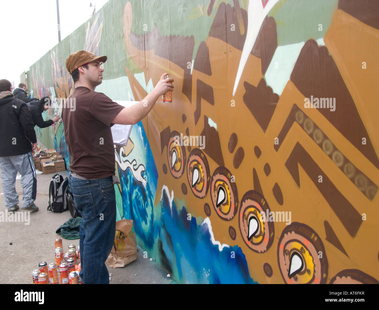 Graffiti artists spray painting building site hoarding Liverpool