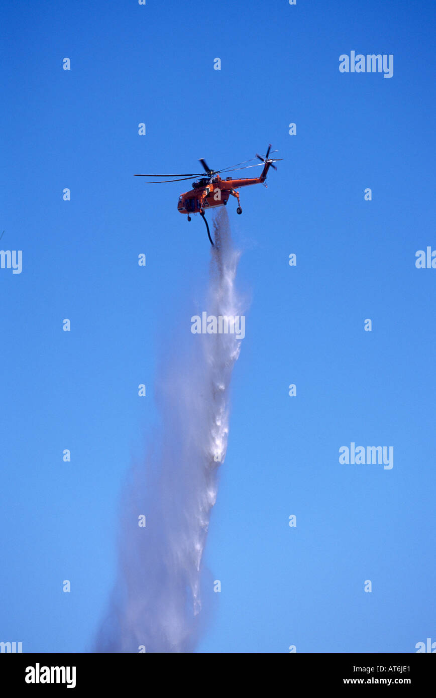 A Helicopter demonstrates dropping Water to fight a Forest Fire in