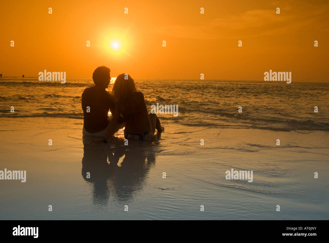 Couple sitting at the beach, silhouetted at sunset, Maldives Stock Photo