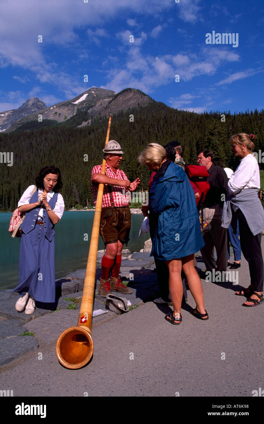Alphorn Blower with Alpenhorn talking to Tourists at Lake Louise, Banff National Park, Canadian Rockies, Alberta, Canada Stock Photo