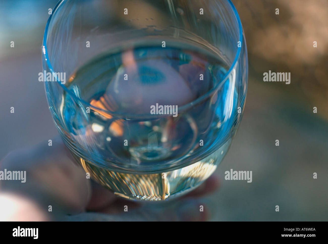 Drinker's eye view into a hand held wineglass containing white wine Stock Photo