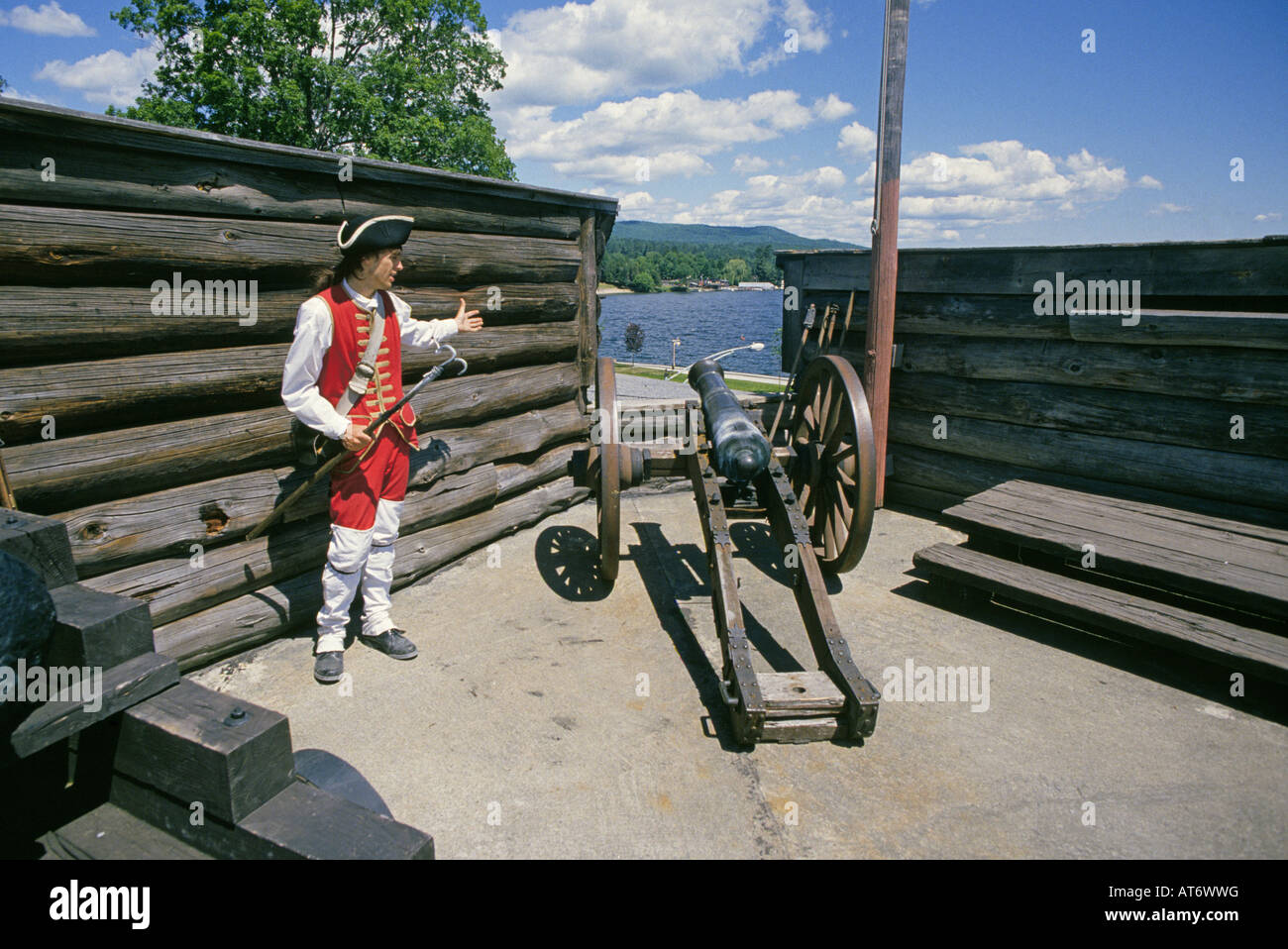 A reenactors dressed as a British soldier stands in front of a cannon at Fort Ticonderoga National Historic Landmark Stock Photo