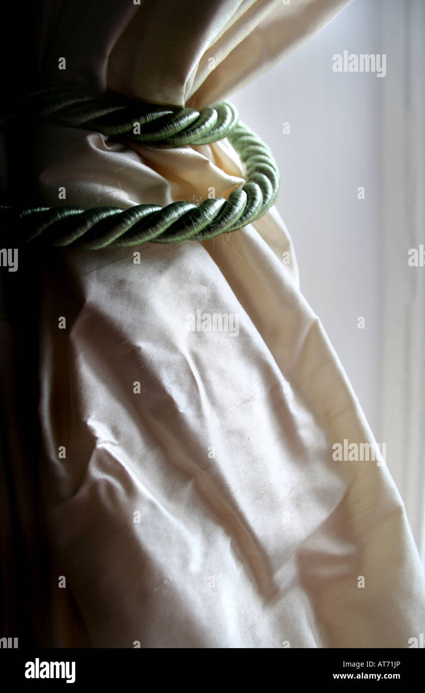 Coiled Rope Drapery Rope curtain tie around cream satin drapes Stock Photo - Alamy