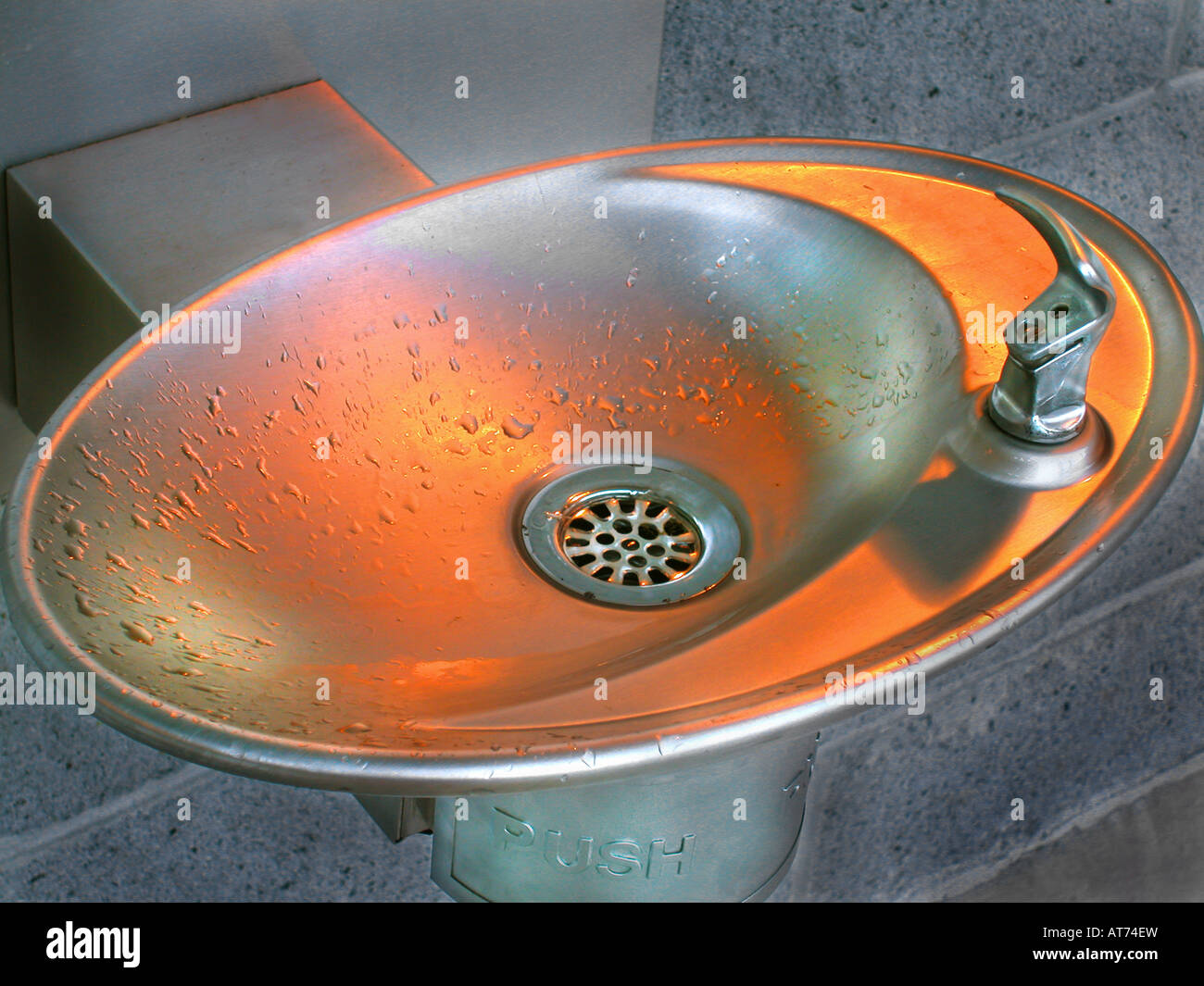 stainless steel water fountain reflecting orange light Stock Photo