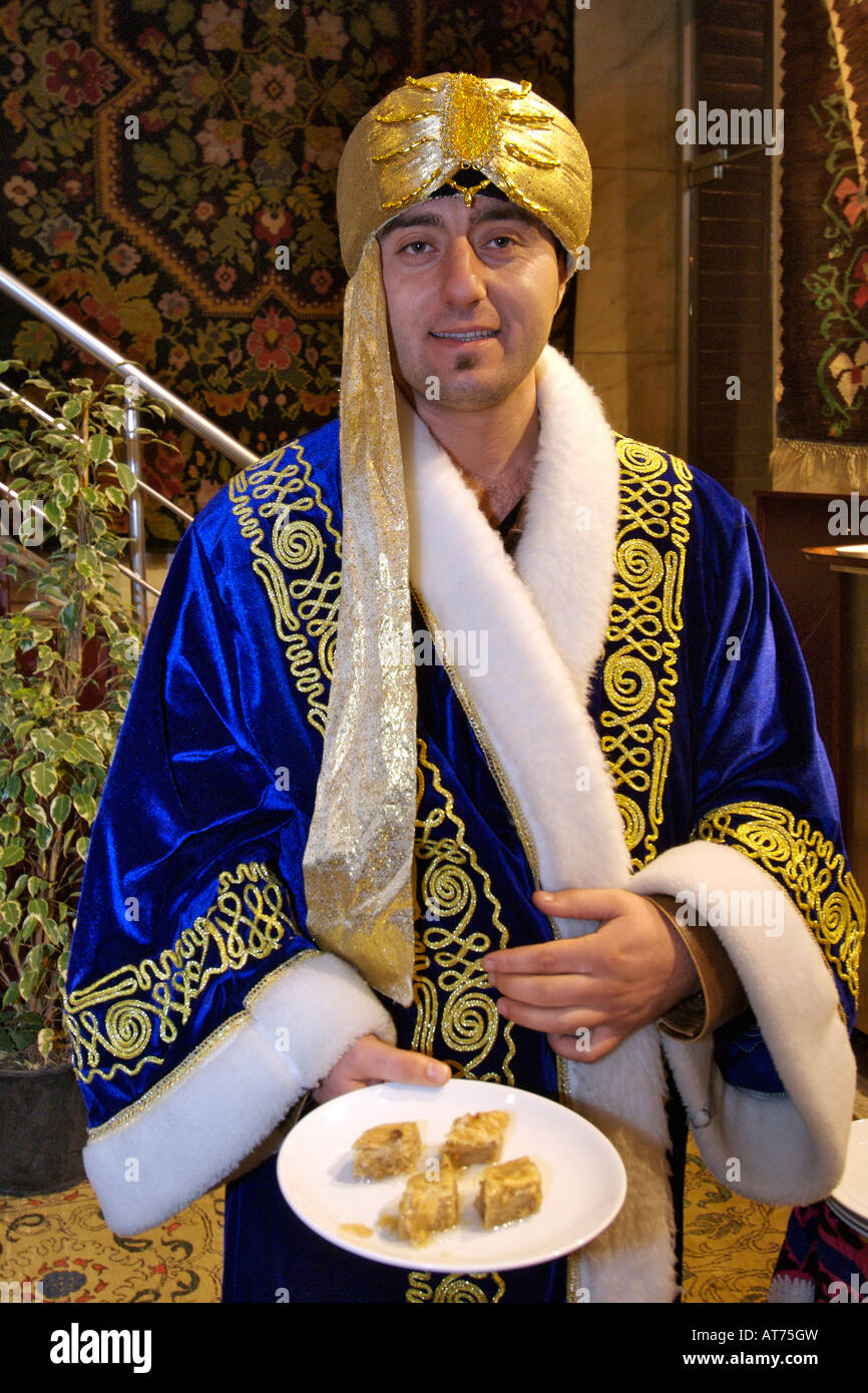 Turkish restaurant host dressed in robe and holding a plate of baklava in  Istanbul Stock Photo - Alamy