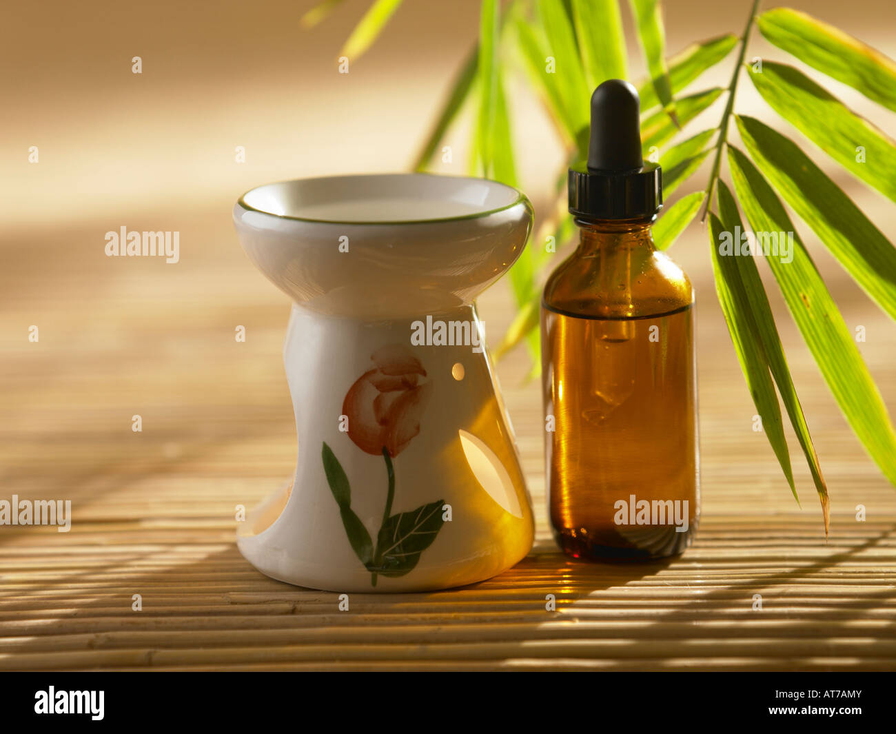 Essential oil burner and bottle on bamboo mat Stock Photo