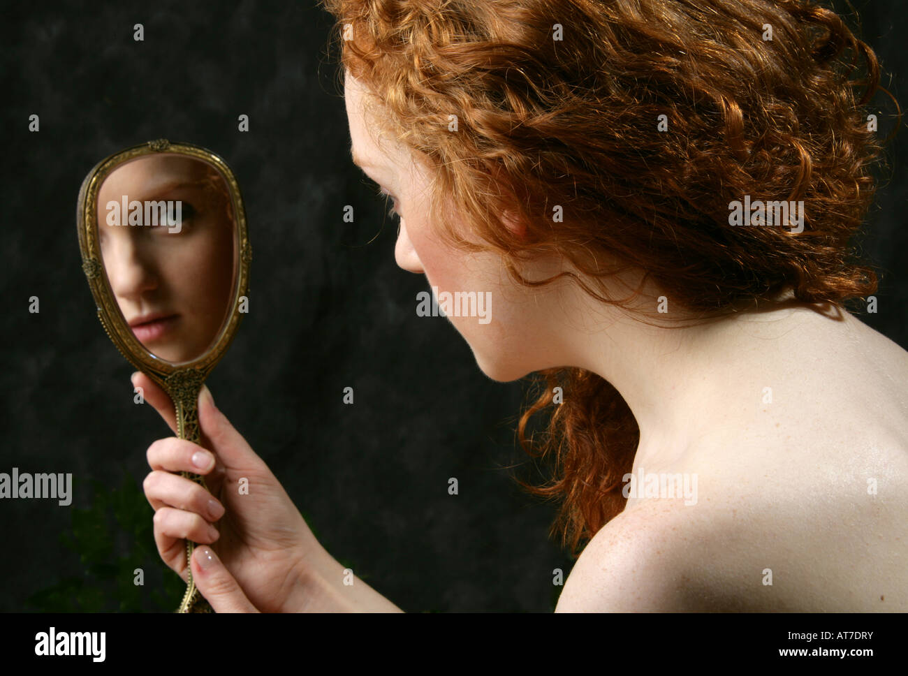 Portrait of a Young Red Haired Girl Looking in a Mirror Stock Photo