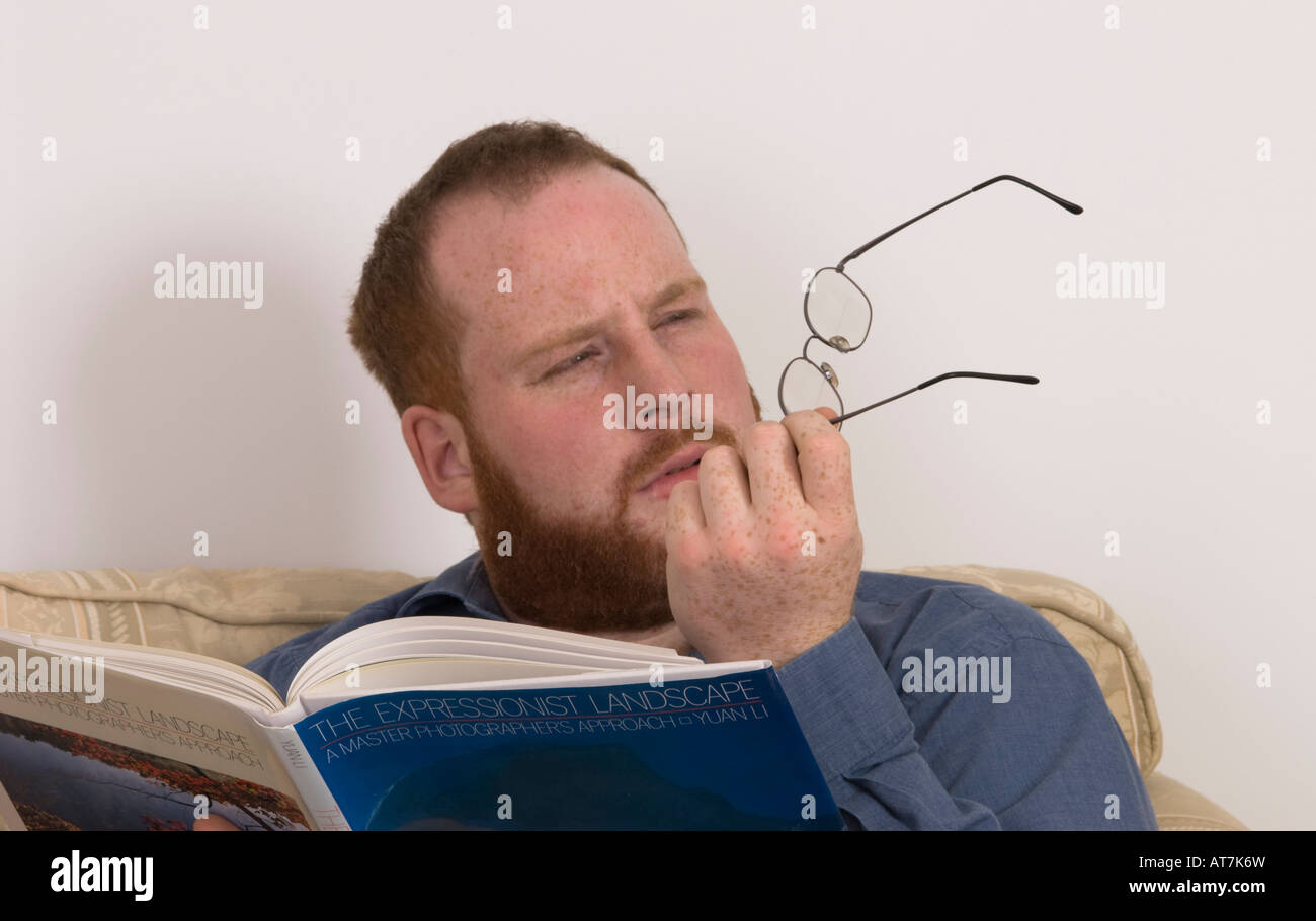 young man straining eyes after removing glasses, are they correct spectacles, correct prescription Stock Photo