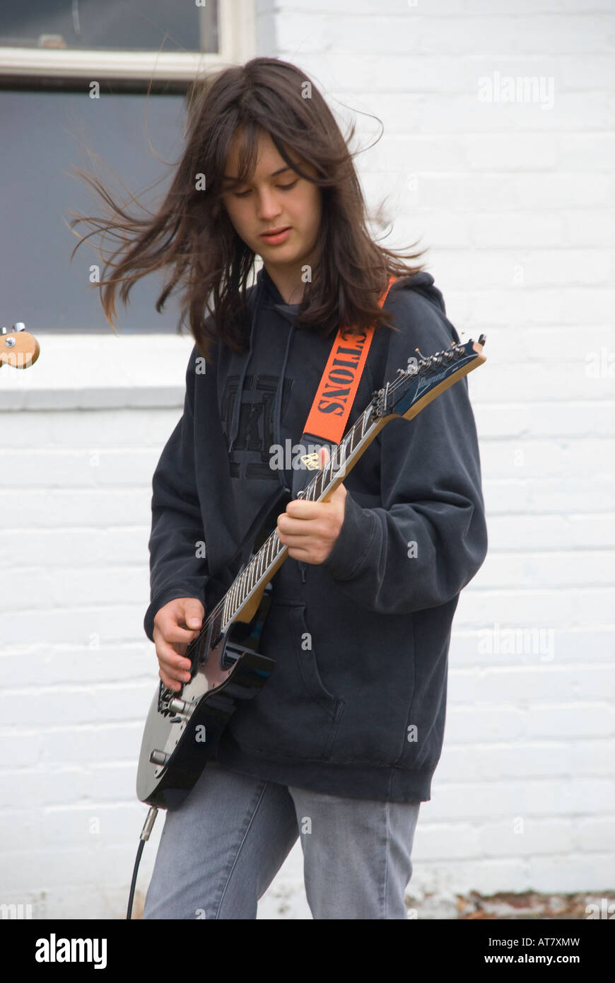 Long haired young boy playing guitar in high school heavy metal band Stock Photo