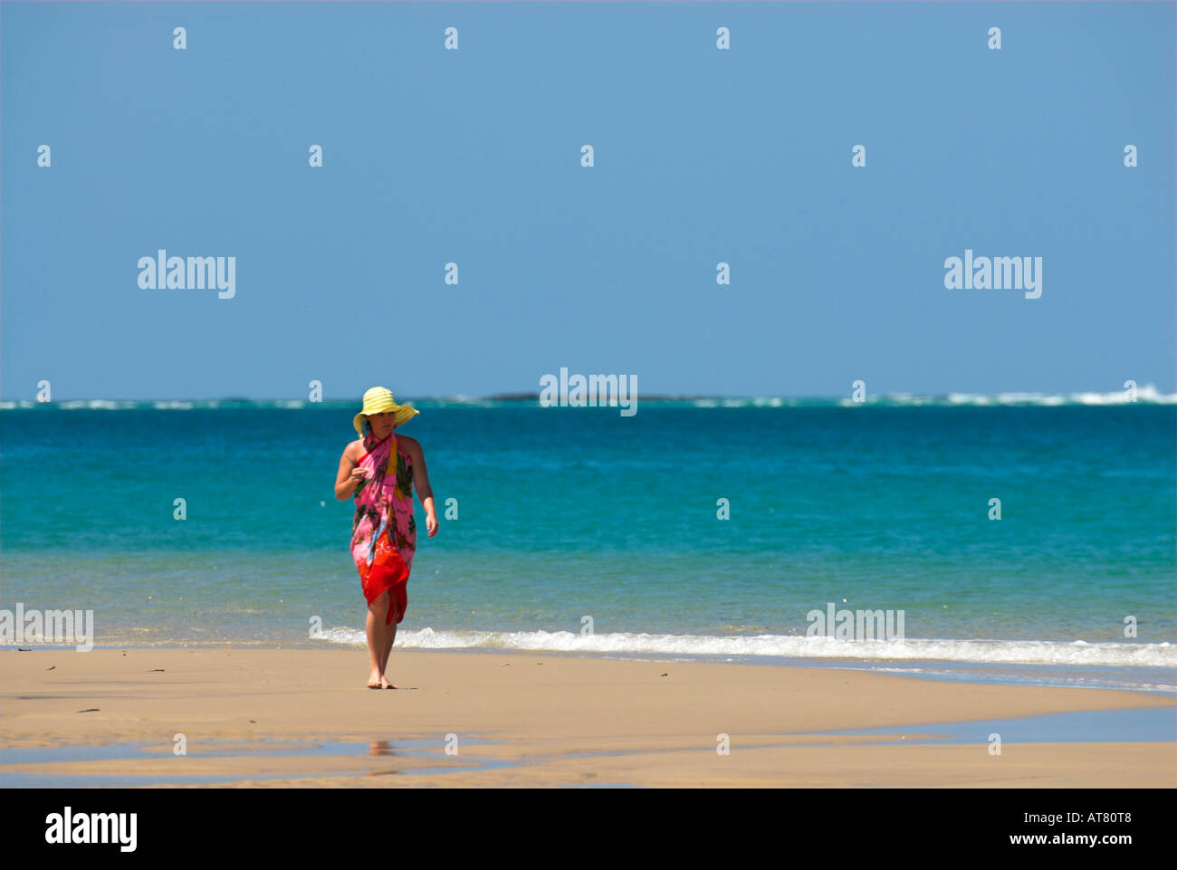 young woman walking on the beach in colourful sarong. Stock Photo