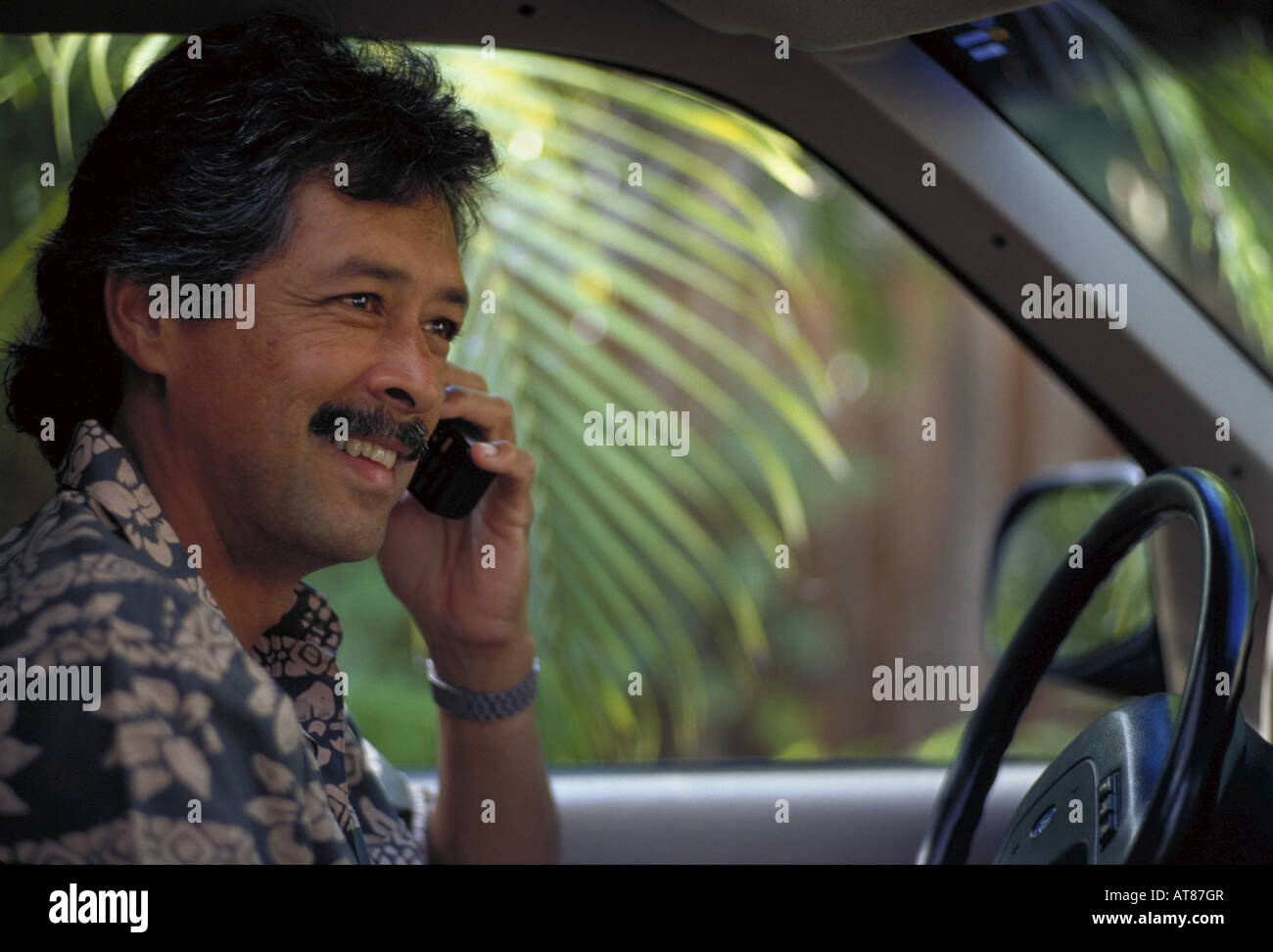 Honolulu businessman talking on cellular phone while stting in his car. Stock Photo