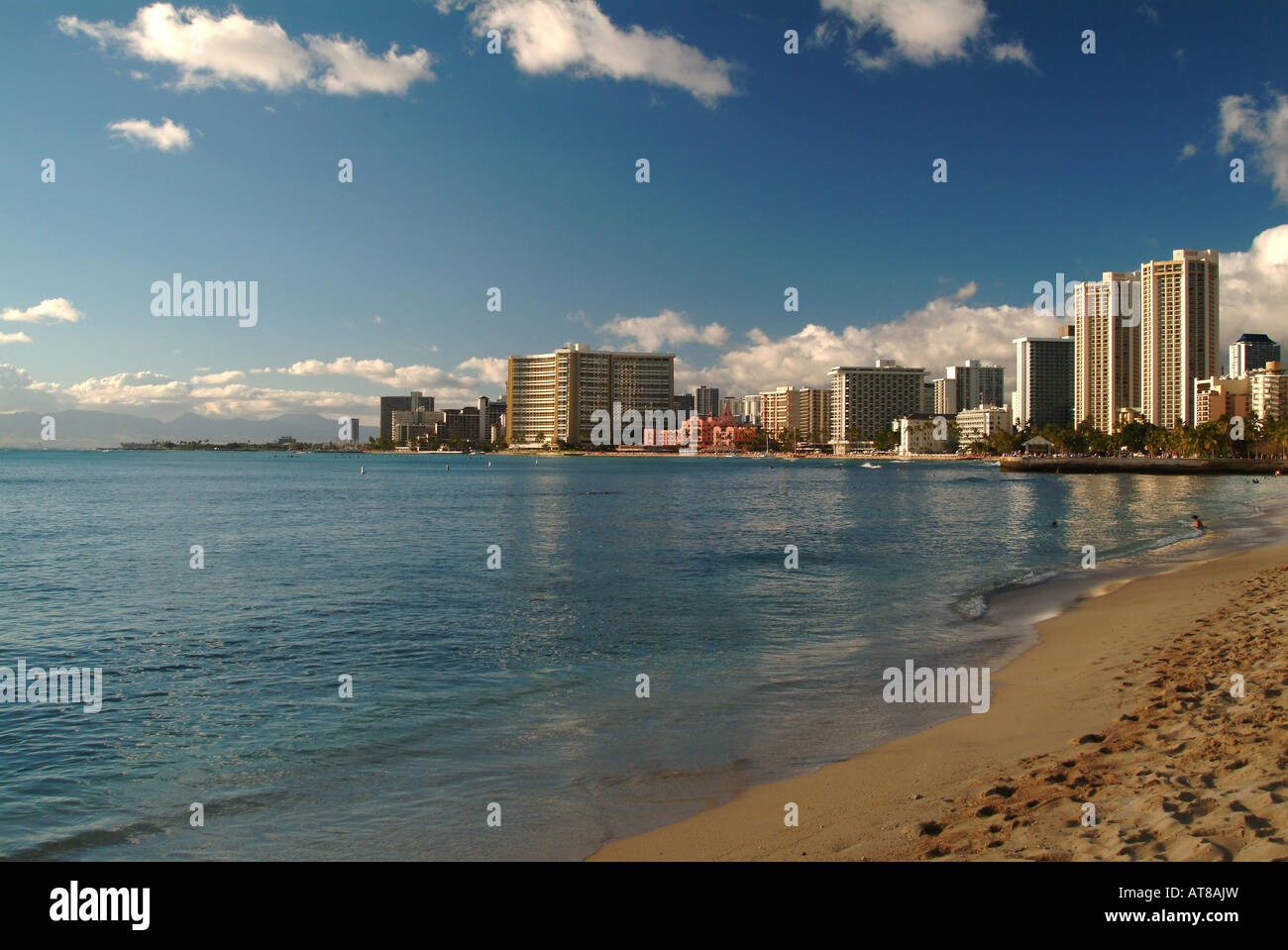 The hotel lined strip of Waikiki Beach with sand and calm ocean in the ...