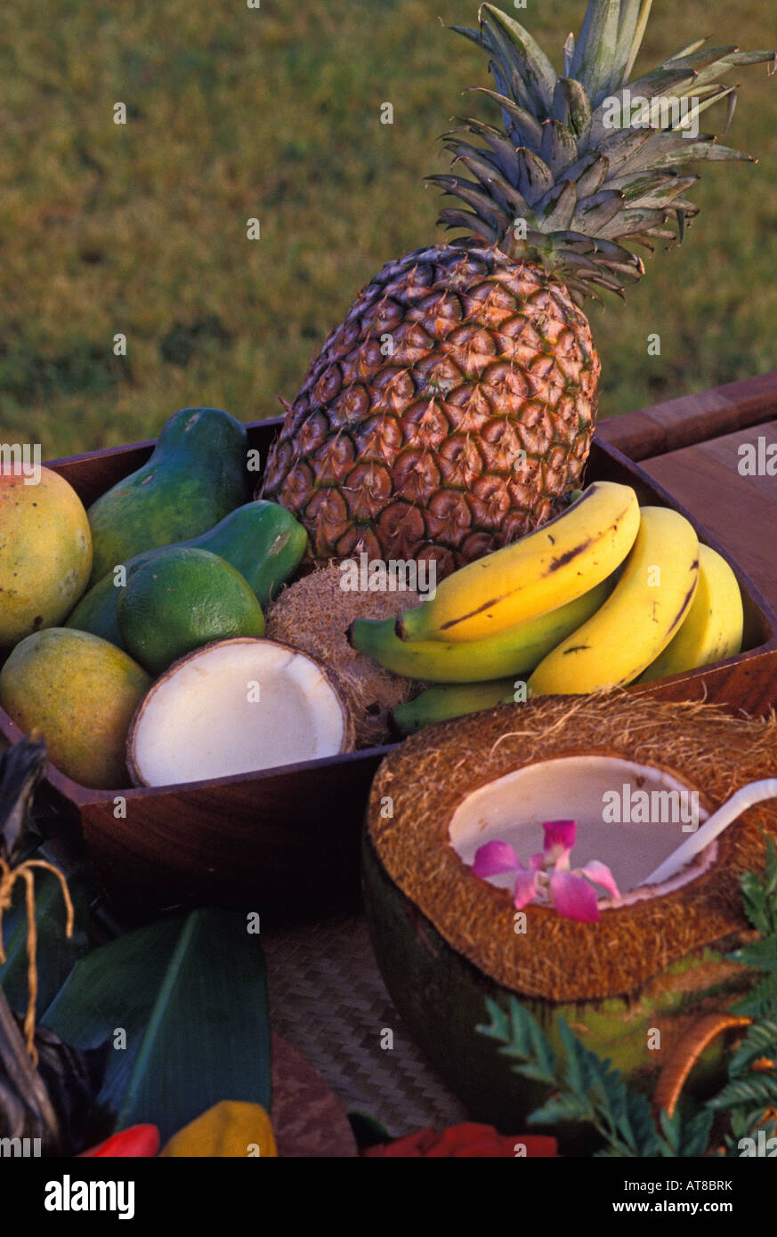 delectable assortment of just picked from the tree tropical fruits arranged inside a dark wood tray and accompanied by a halved Stock Photo