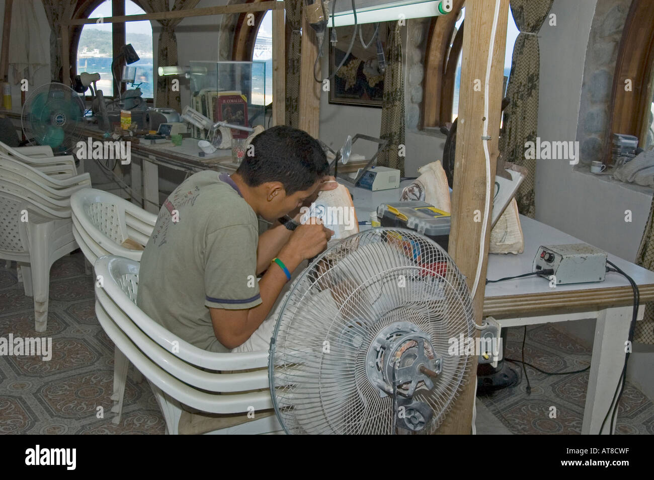 Young worker painting on sea shell in Roatan town Cameo factory 