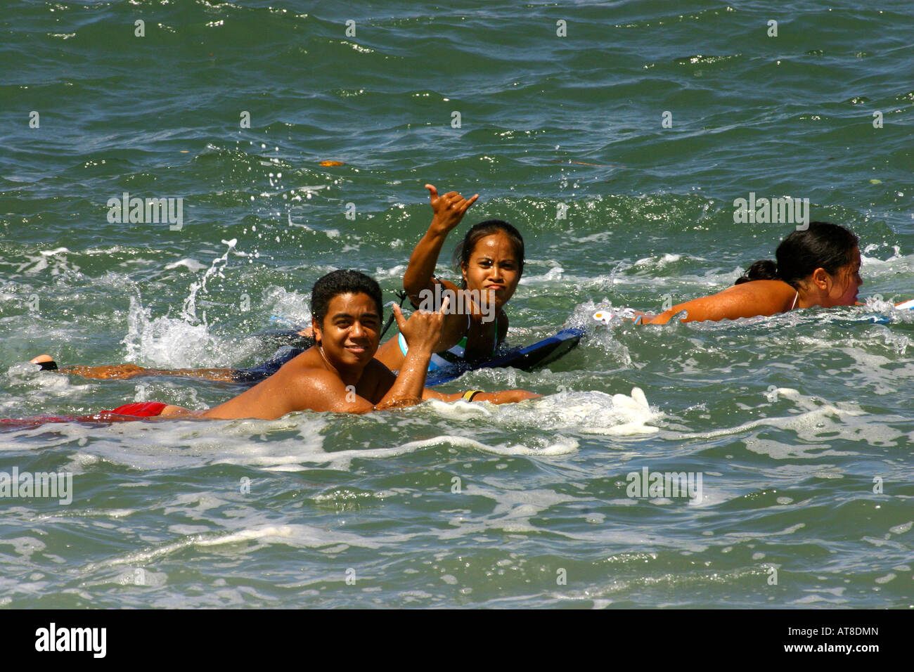 Group of boogie boarders wave shaka sign while paddling out to popular ...