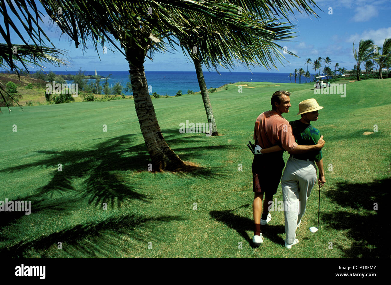 Couple walk with theirs arms around each other on the green turf of a golf course on Oahu. Stock Photo