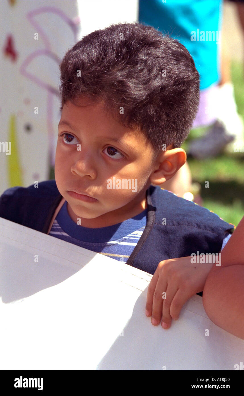Sad tired Latino boy age 5 marching in parade. In the Heart of the Beast May Day Festival and Parade Minneapolis Minnesota USA Stock Photo