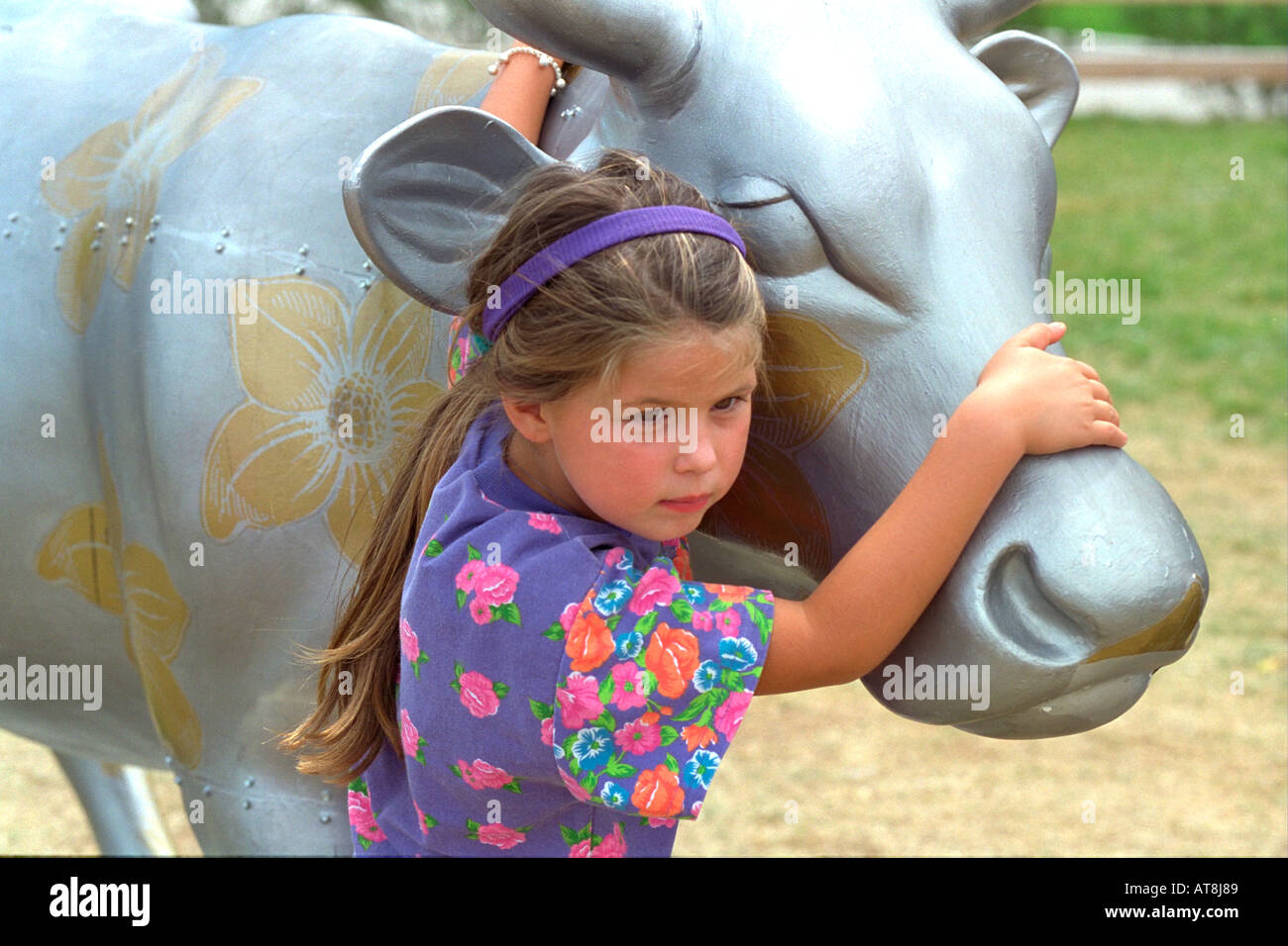 Girl age 5 playing on decorated art sculpture of cow. Cows on Parade Chicago Illinois USA Stock Photo