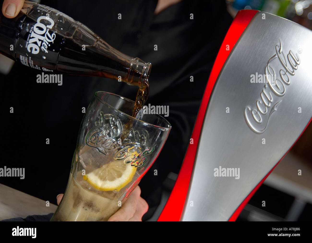 barperson pouring a diet coke into a glass with ice and la slice of lemon Stock Photo