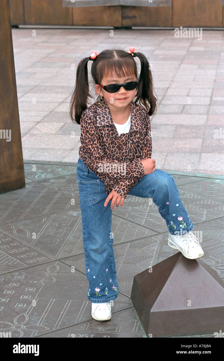 Stylish Asian girl age 6 posing with leg up at Memorial Day Service. St Paul Minnesota USA Stock Photo