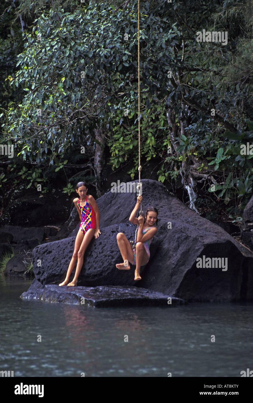 Girls jumping from rope swing into pool. Kalihiwai River, North shore