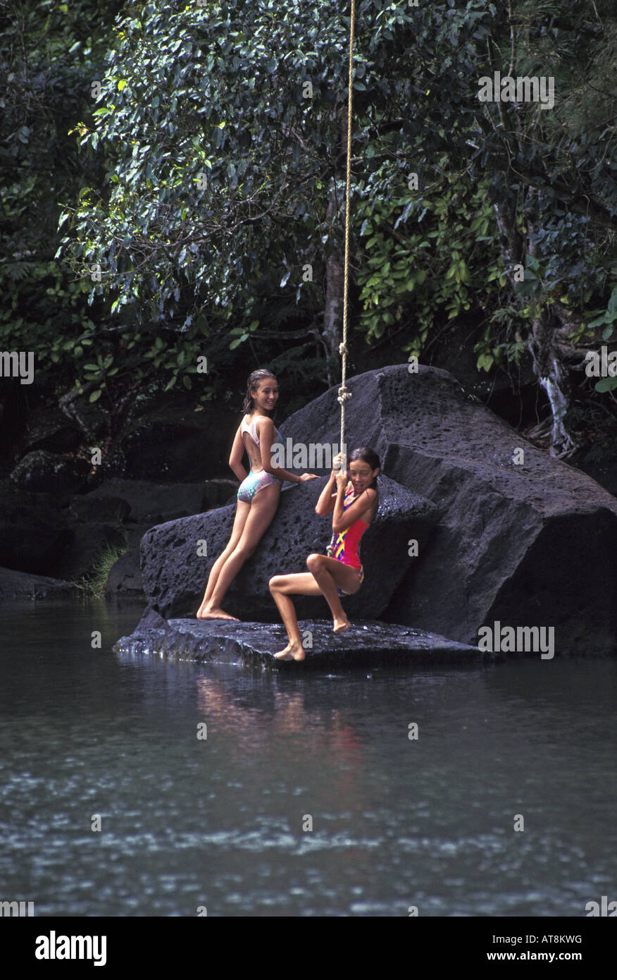Girls jumping from rope swing into pool. Kalihiwai River, North shore