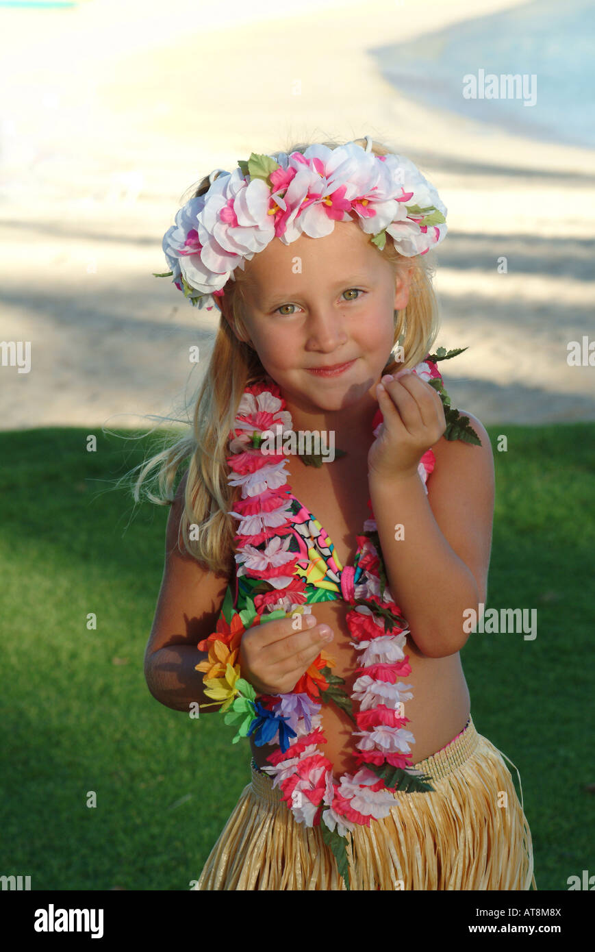Young girl visiting the islands wearing a hula skirt and dancing on the