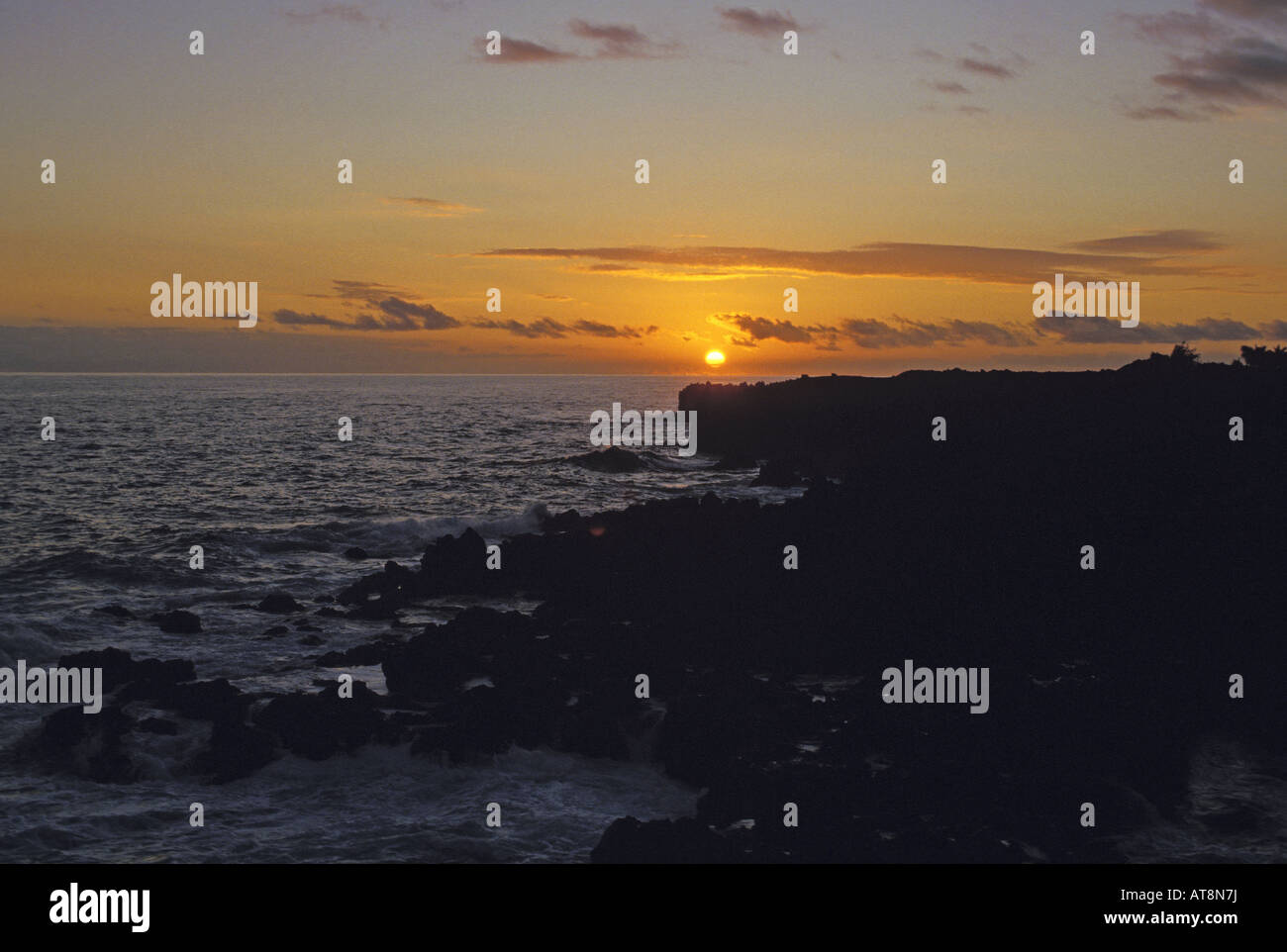 A golden sunrise over the Pacific Ocean in front of the rugged ...