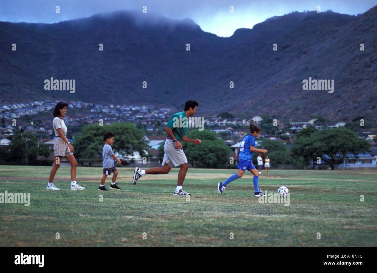 Family playing soccer in an open field in Hawaii Kai, Oahu Stock Photo