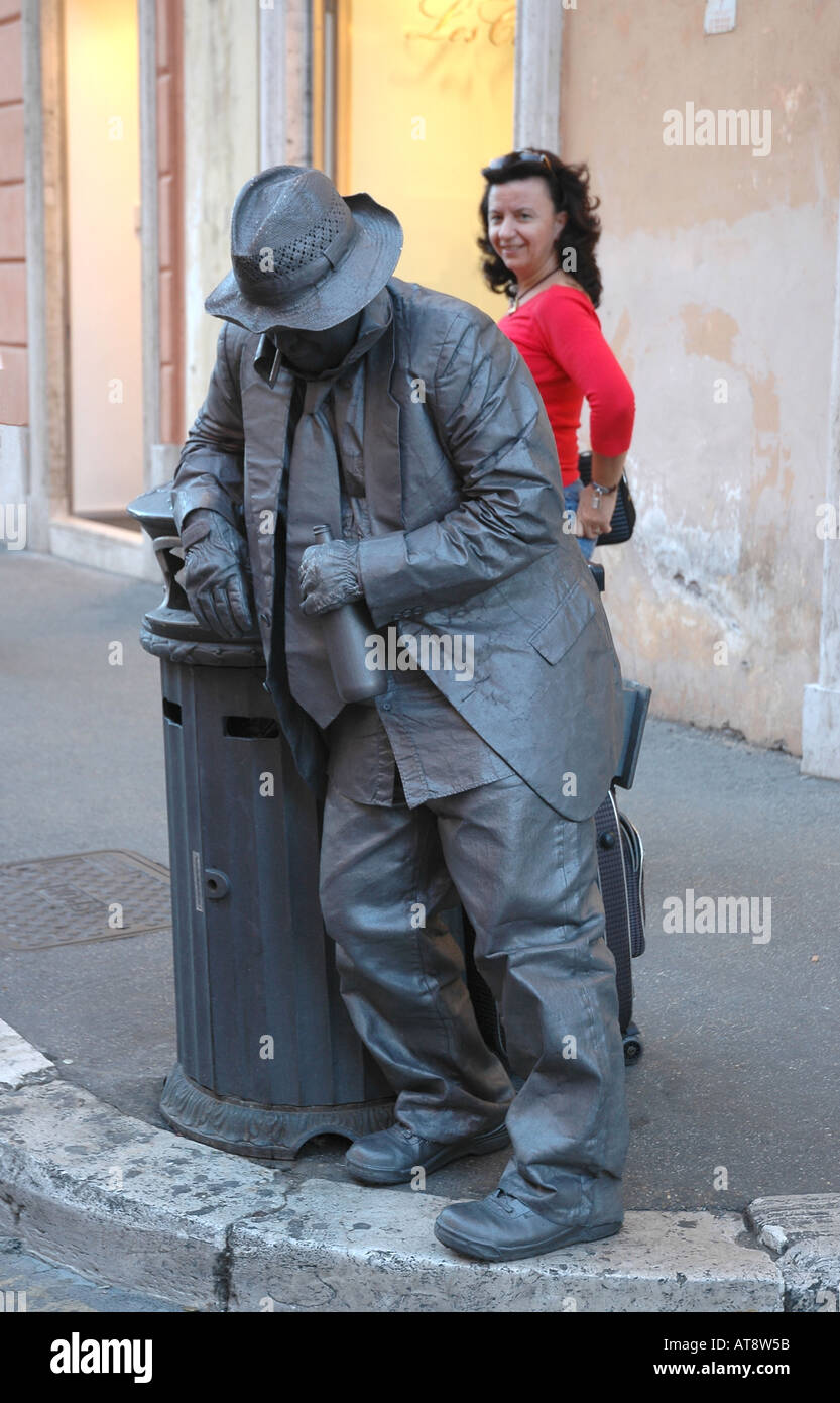 A 'living statue' in Rome portrays a drunk, to the amusement of a woman passing by Stock Photo