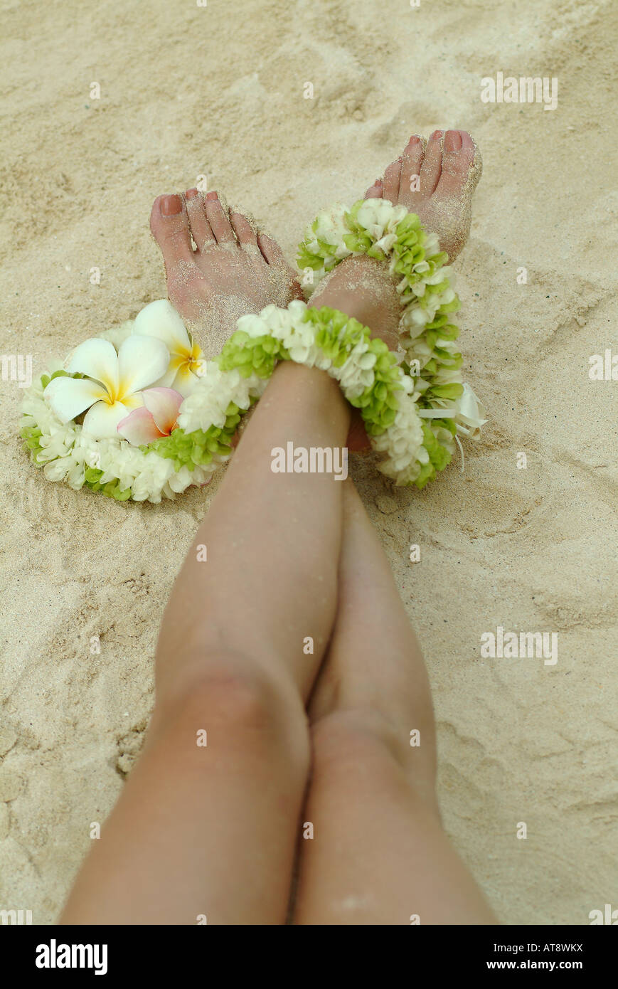 Close up of womans feet with plumeria flowers, draped with flower lei Stock Photo