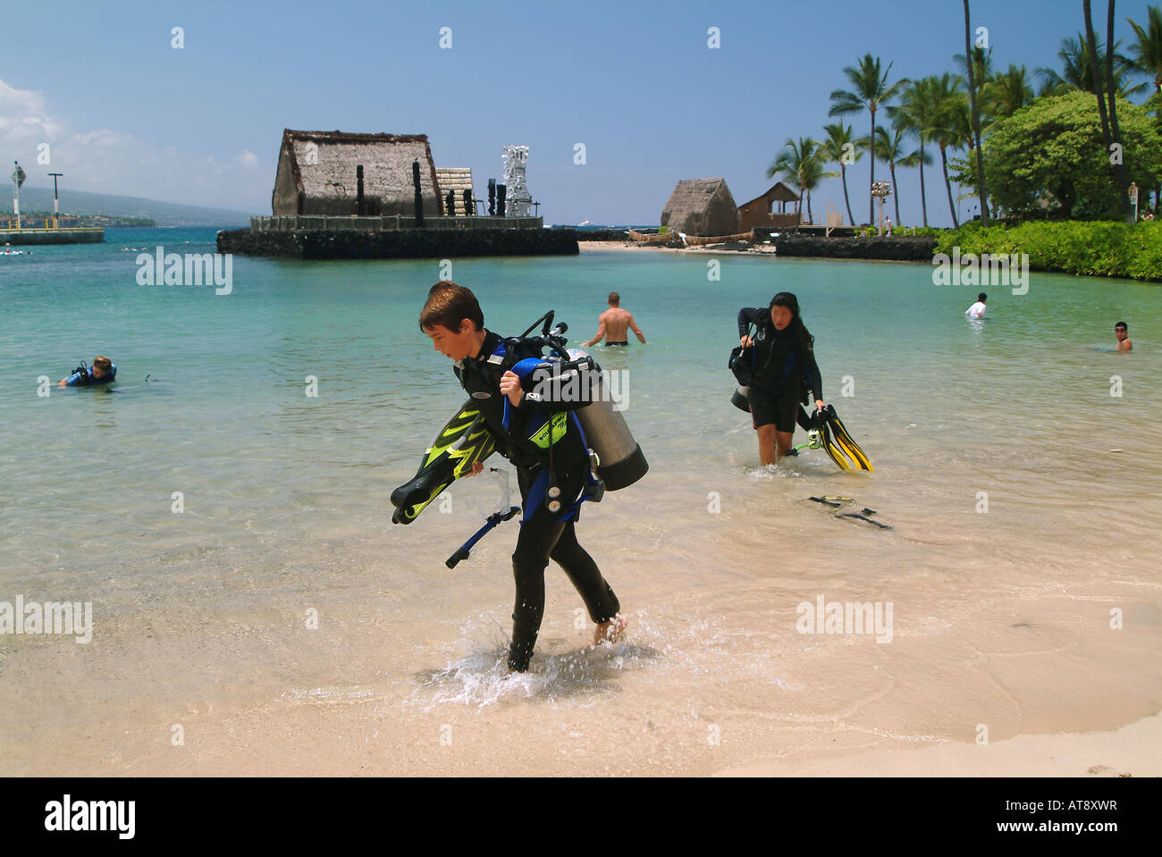 Scuba divers coming out of ocean at Kamakahonu beach near the King Kamehameha hotel near Ahuena heiau, the kings temple refuge Stock Photo