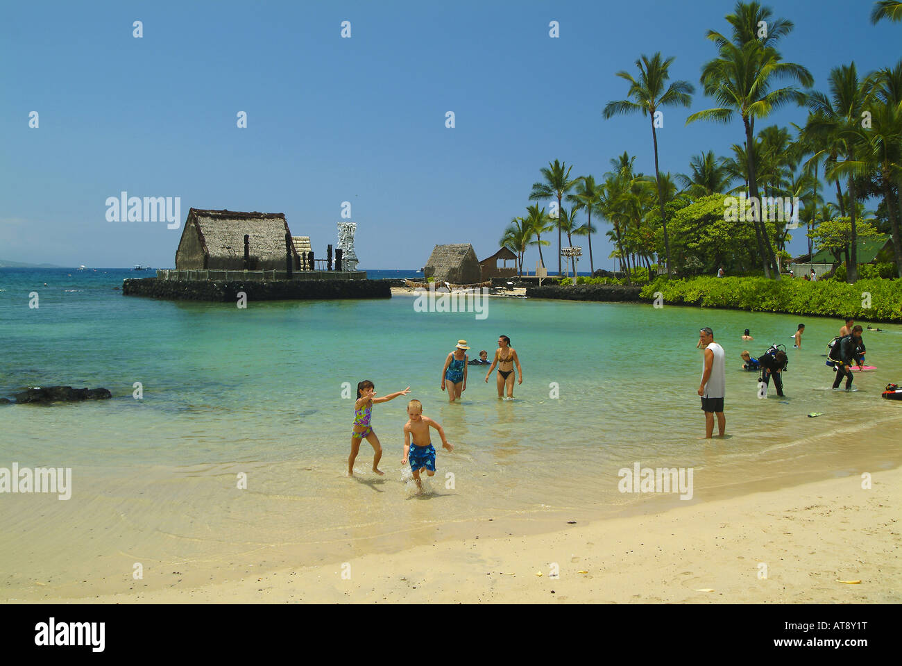People at Kamakahonu beach near the King Kamehameha hotel with Ahuena heiau, the kings temple refuge in rear Stock Photo