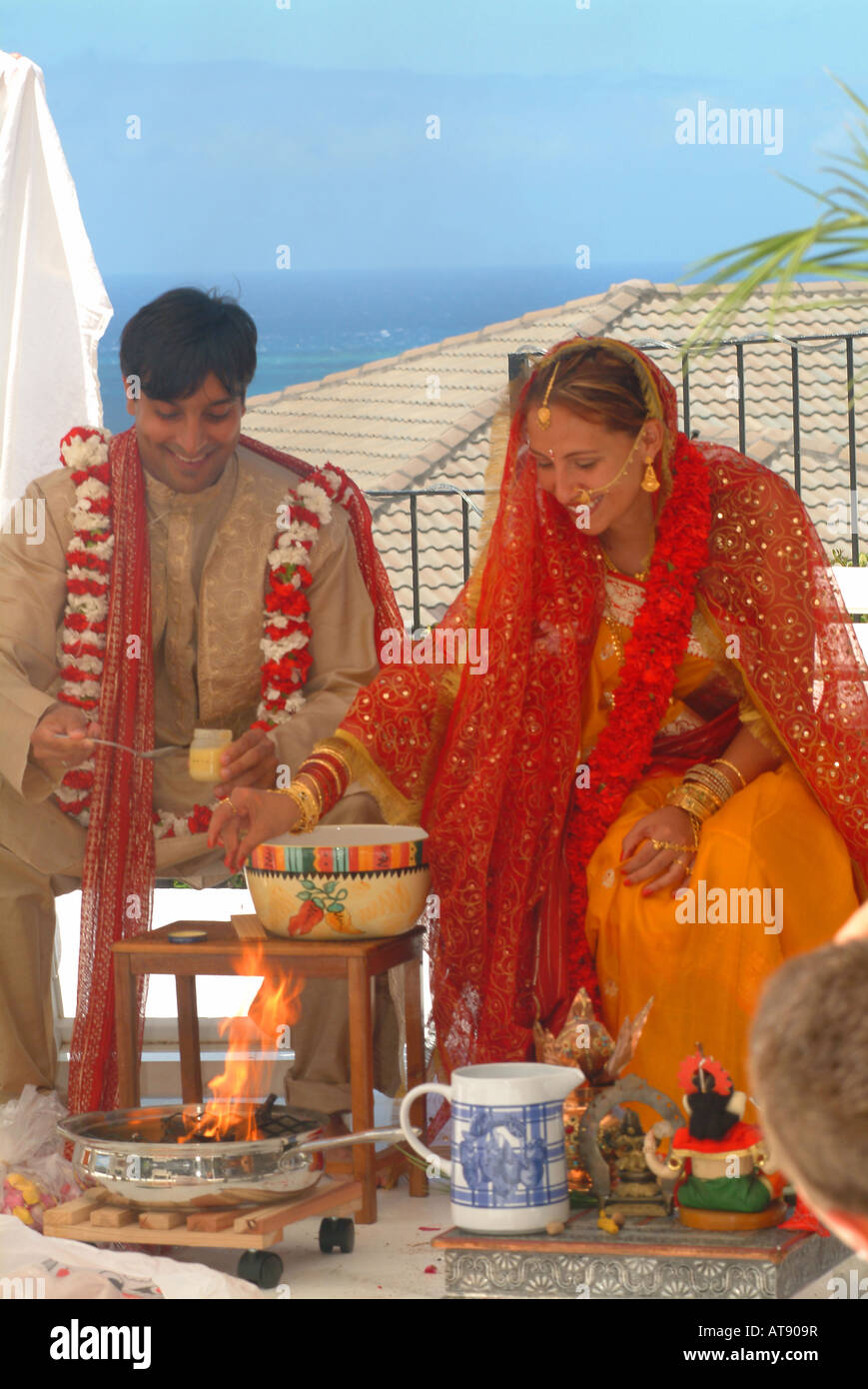 Tradditional Hindi wedding with groom wearing carnation flowers and bride with indian adornments Stock Photo