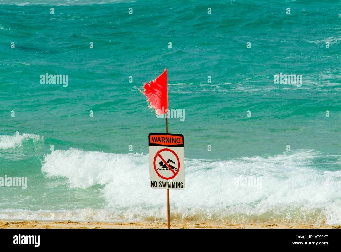 A red flag warns swimmers of high surf at the north shore on the island of Oahu. Stock Photo