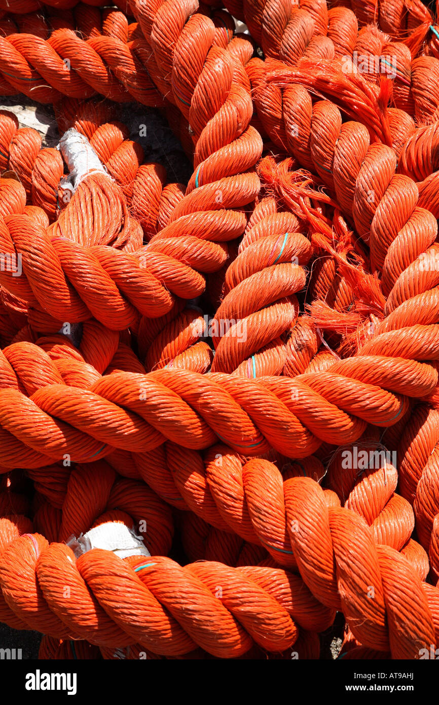 Section of thick orange rope lying in massed loops with tape around the ends of the rope.  Close up. Stock Photo