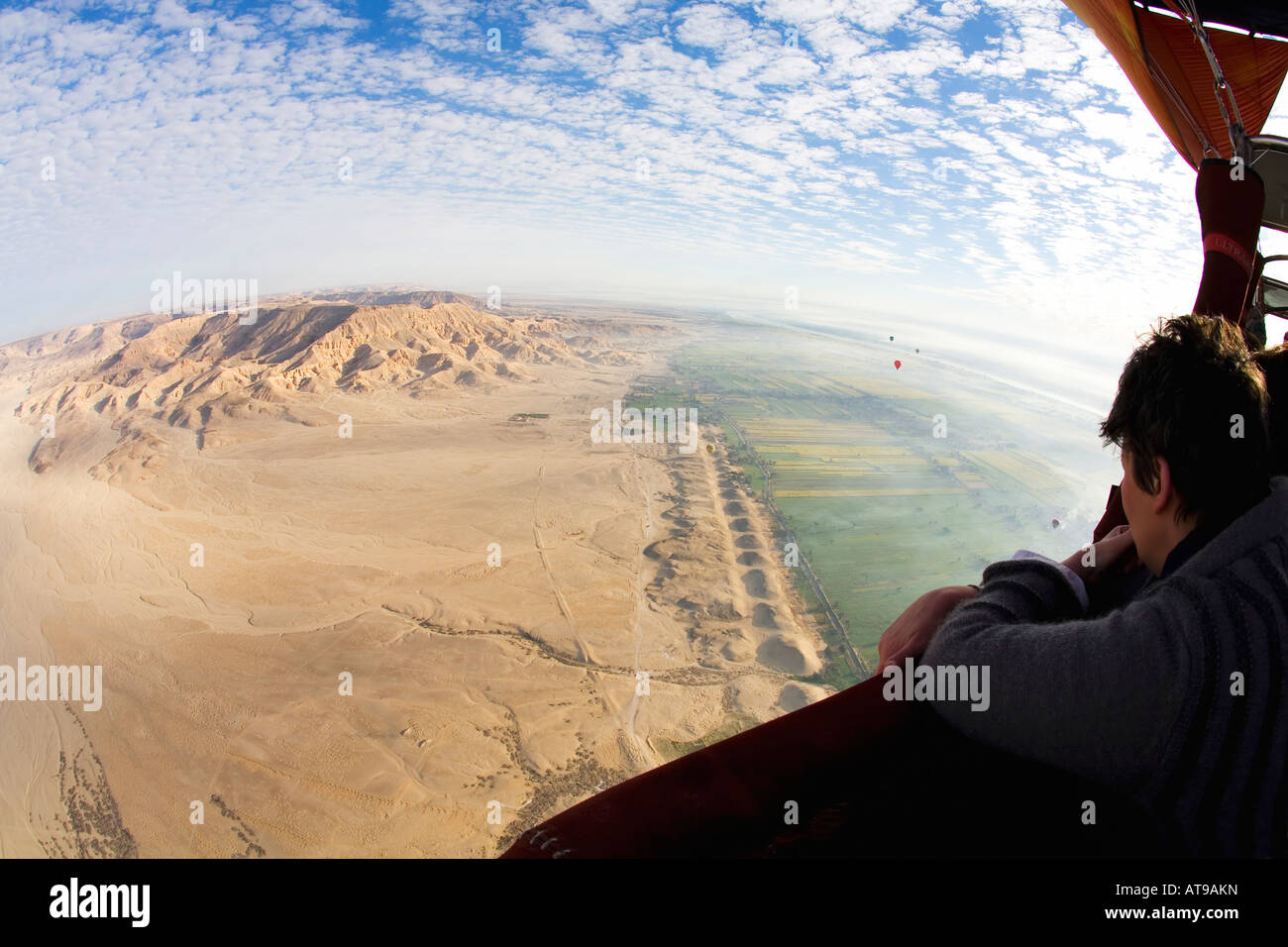 Tourist in hot air balloon admires aerial view of Luxor West Bank Theban Mountains Valley of Kings Egypt North Africa Stock Photo