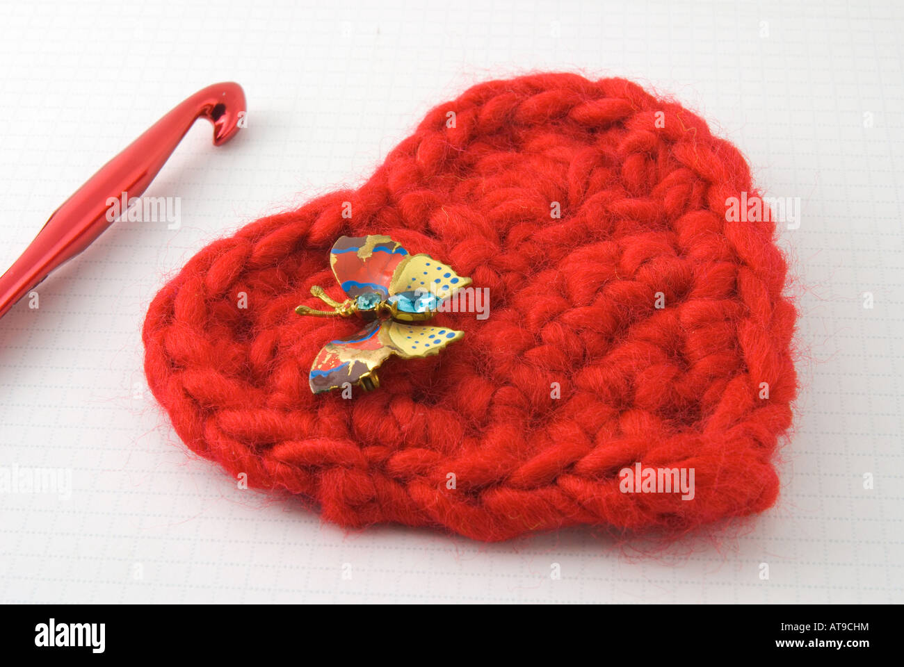 Crocheted red heart with butterfly pin and crochet hook Stock Photo