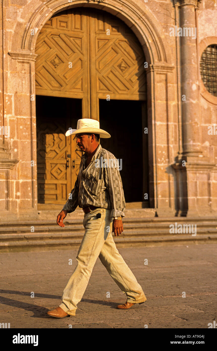 Caballero walking across Plaza San Agustin w facade of Templo de los Augustinos in distance Morelia Michoacan state Mexico Stock Photo